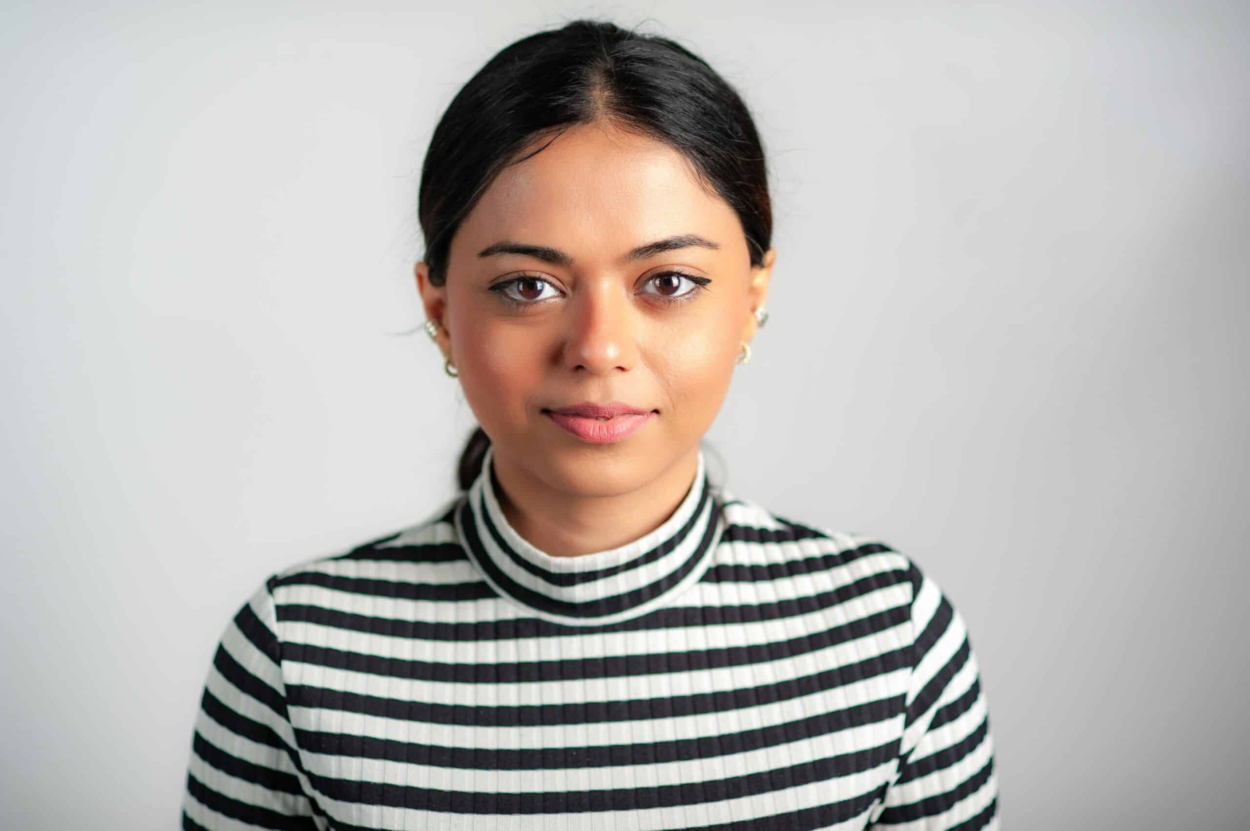 Elegant portrait of an adult woman in a striped turtleneck against a white background.