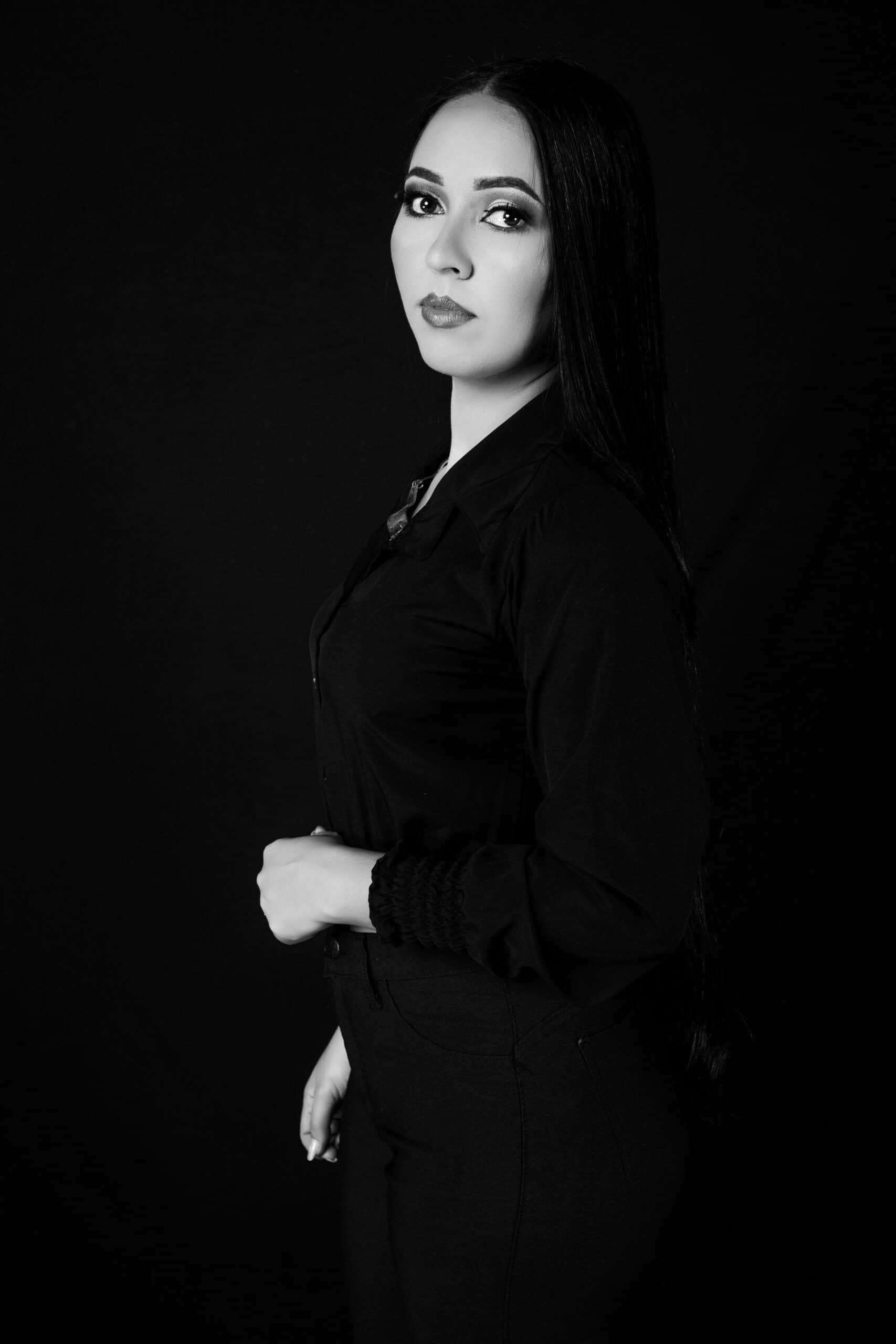 Stylish black and white portrait of an adult woman in a studio setting wearing dark clothing.