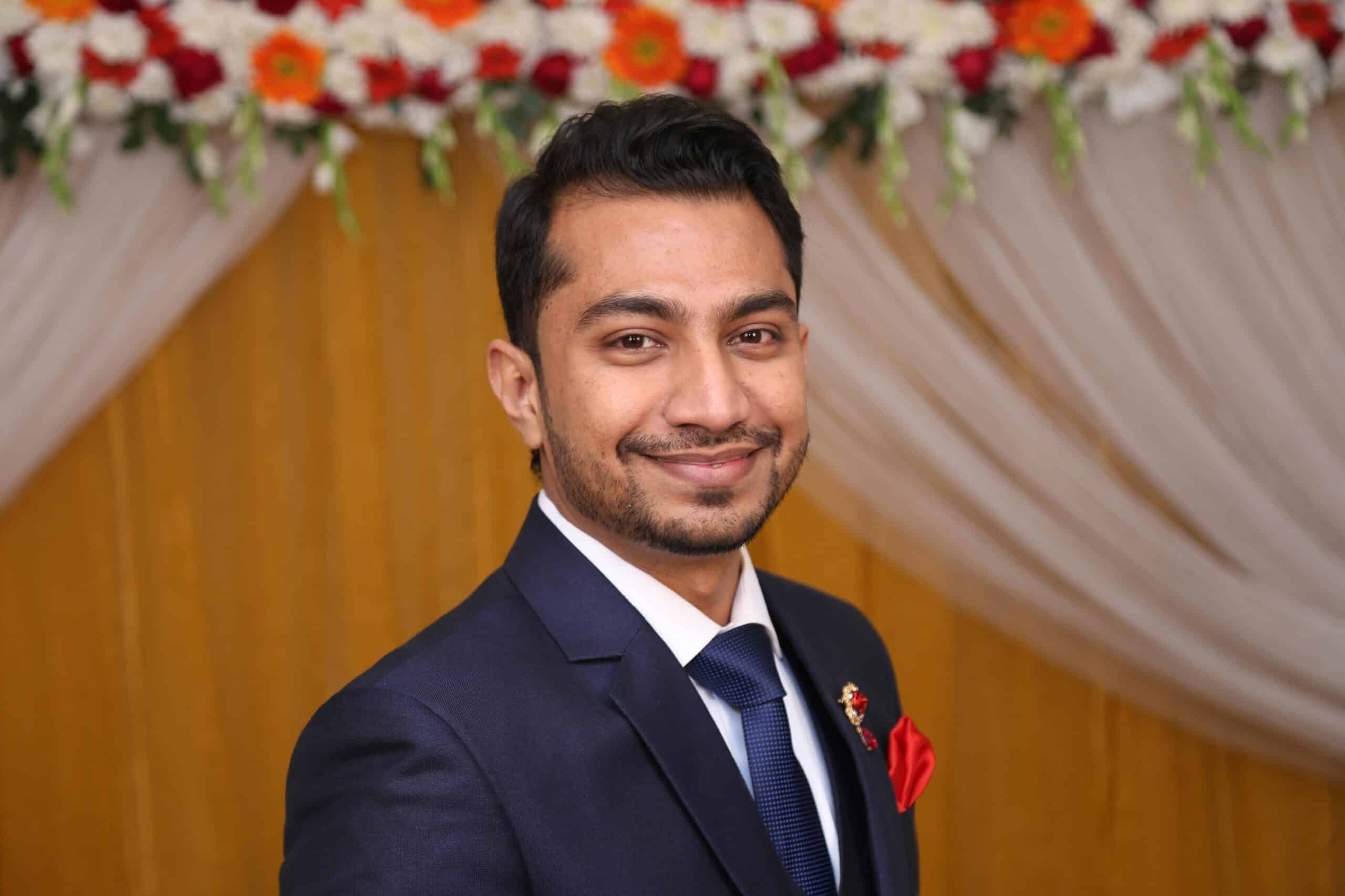 Close-up of a smiling man in a suit at a formal event in Dhaka, Bangladesh.